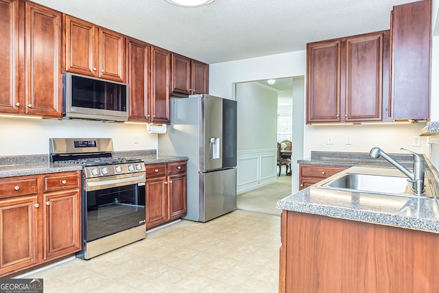 kitchen with a textured ceiling, appliances with stainless steel finishes, and sink