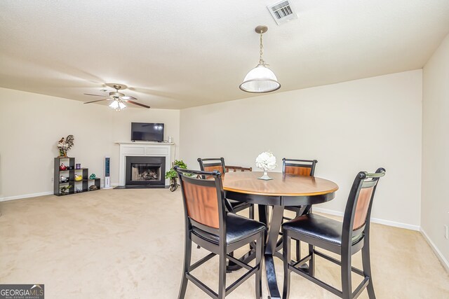 dining room with ceiling fan and light colored carpet