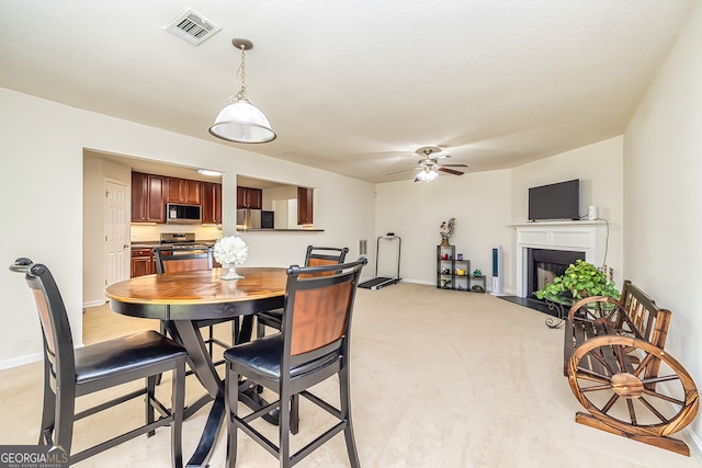 carpeted dining room with a textured ceiling and ceiling fan