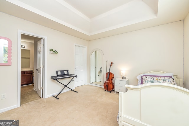 carpeted bedroom with a raised ceiling and connected bathroom