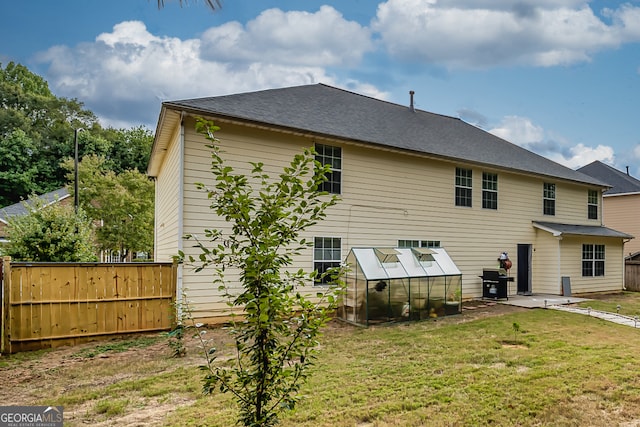 rear view of property featuring a lawn, an outbuilding, and a patio