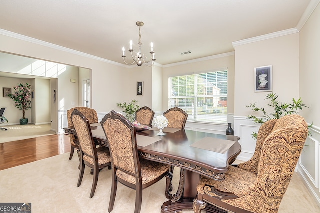 dining area featuring crown molding, light hardwood / wood-style floors, and an inviting chandelier