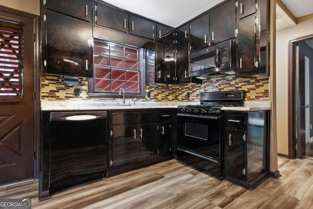 kitchen with light wood-type flooring, black appliances, backsplash, and sink