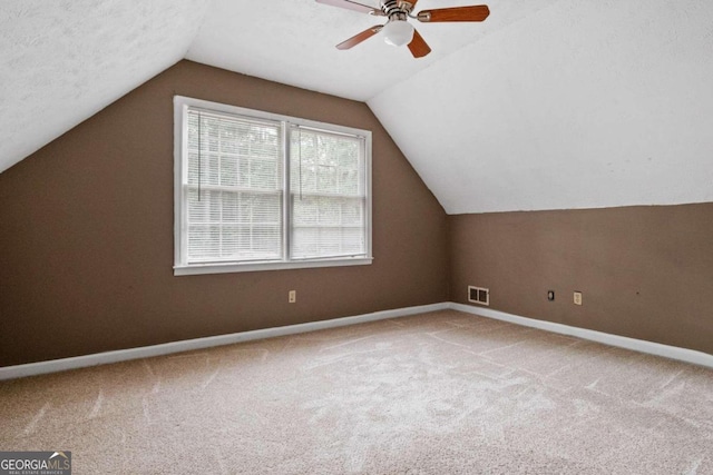 bonus room featuring ceiling fan, carpet floors, lofted ceiling, and a textured ceiling