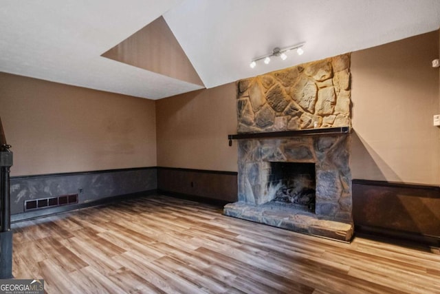 unfurnished living room with wood-type flooring, a fireplace, and track lighting