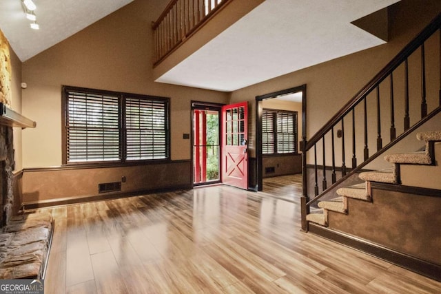 foyer featuring light wood-type flooring and high vaulted ceiling