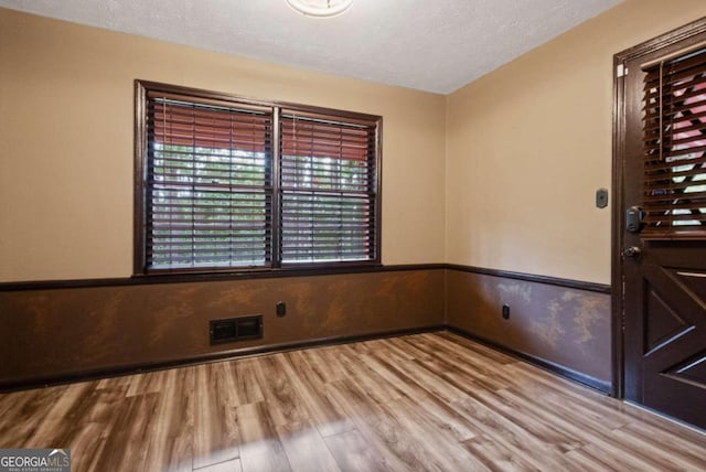 spare room with light wood-type flooring and a textured ceiling