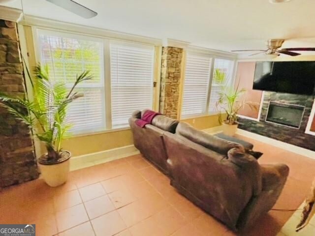 living room with ceiling fan, light tile patterned flooring, and a large fireplace