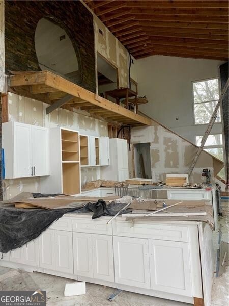 kitchen featuring vaulted ceiling and white cabinetry