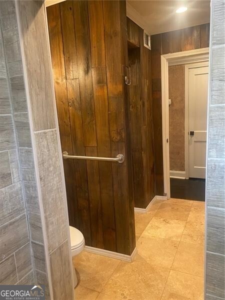 bathroom with wooden walls and toilet