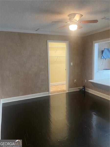 spare room with a textured ceiling, ornamental molding, and ceiling fan