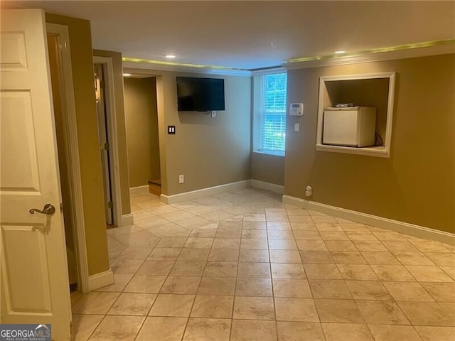 empty room with crown molding and light tile patterned floors