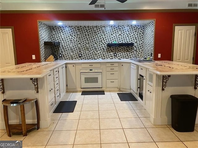 kitchen with white appliances, light tile patterned floors, kitchen peninsula, and ceiling fan