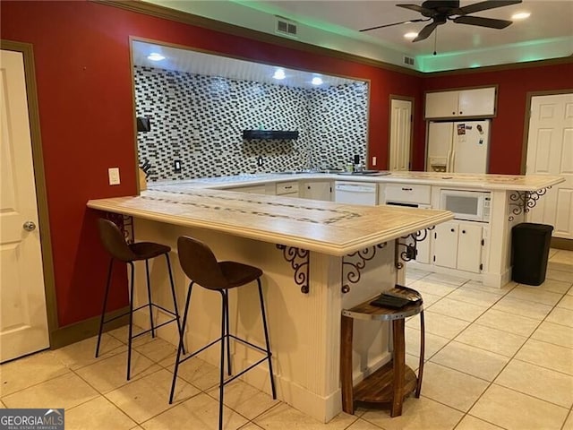 kitchen with a kitchen breakfast bar, white cabinetry, kitchen peninsula, and ceiling fan