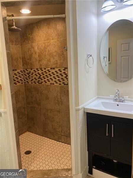 bathroom with a tile shower and vanity