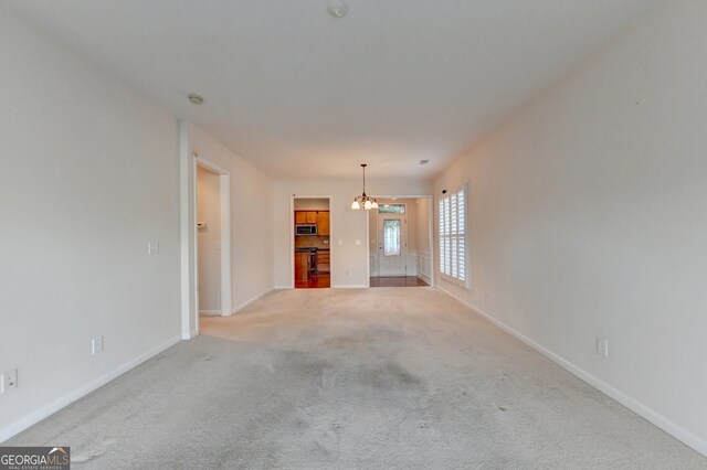 unfurnished living room featuring an inviting chandelier and light colored carpet