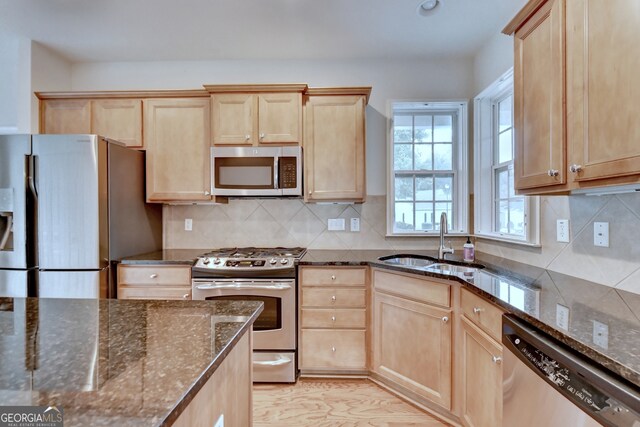 kitchen with backsplash, dark stone countertops, sink, and stainless steel appliances