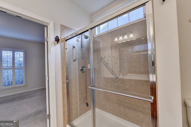 bathroom with a shower with shower door and toilet