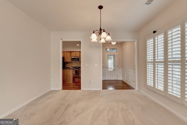 unfurnished dining area featuring an inviting chandelier and carpet floors