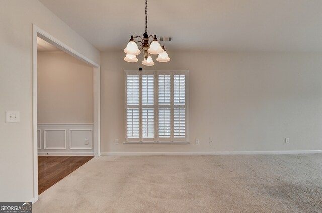 carpeted spare room featuring an inviting chandelier