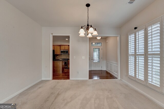 unfurnished dining area featuring an inviting chandelier and carpet