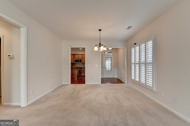 unfurnished dining area featuring an inviting chandelier and carpet