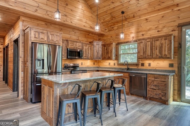 kitchen with appliances with stainless steel finishes, plenty of natural light, lofted ceiling, and a center island