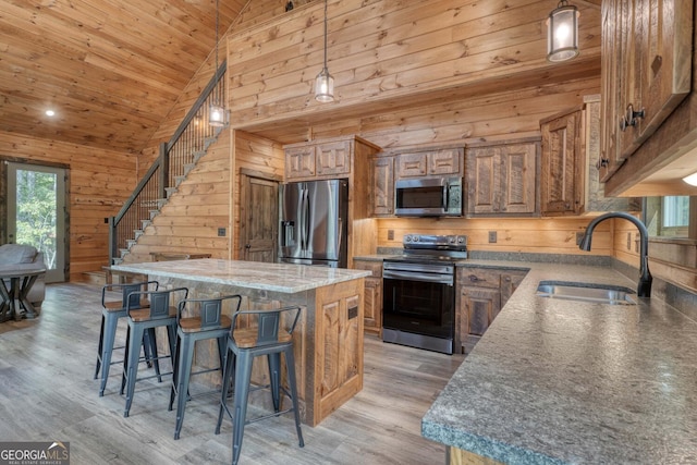 kitchen with sink, hanging light fixtures, a kitchen island, light hardwood / wood-style flooring, and stainless steel appliances