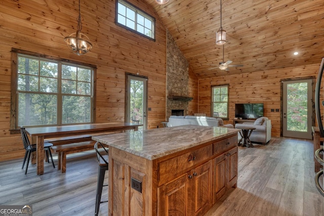 kitchen featuring a fireplace, a wealth of natural light, pendant lighting, and high vaulted ceiling