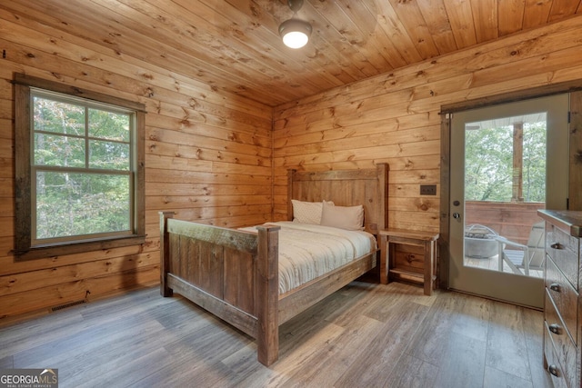 bedroom with wood-type flooring, wood walls, and multiple windows