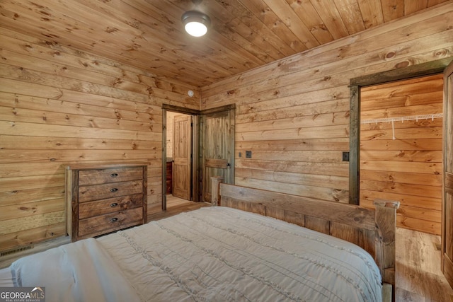 bedroom with light hardwood / wood-style flooring, wooden walls, and wooden ceiling