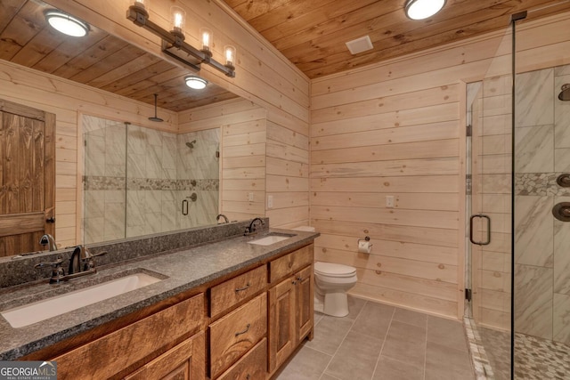 bathroom with a shower with shower door, vanity, wooden walls, toilet, and tile patterned floors