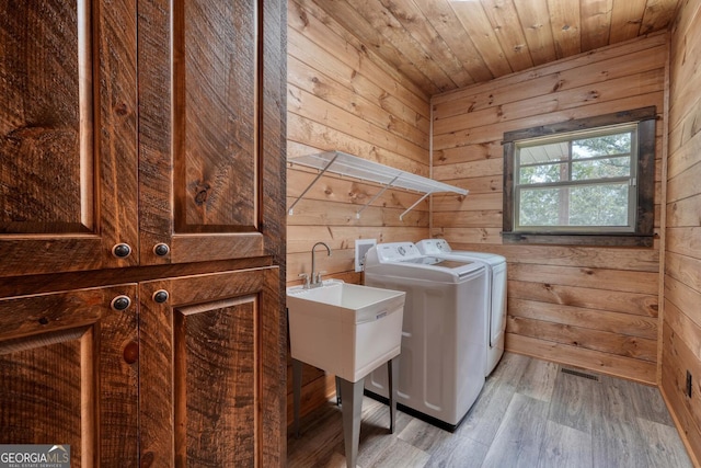 washroom with wooden ceiling, light hardwood / wood-style floors, wood walls, and washing machine and clothes dryer