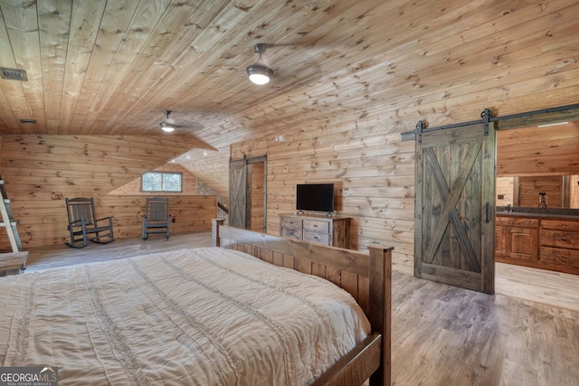 bedroom featuring wood ceiling, light hardwood / wood-style floors, a barn door, lofted ceiling, and wooden walls