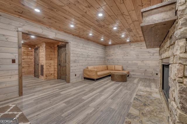 unfurnished room with wood ceiling, wooden walls, light hardwood / wood-style floors, and a fireplace