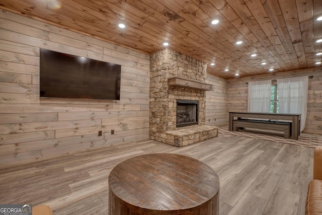 living room with wood ceiling, a fireplace, wood walls, and light hardwood / wood-style flooring