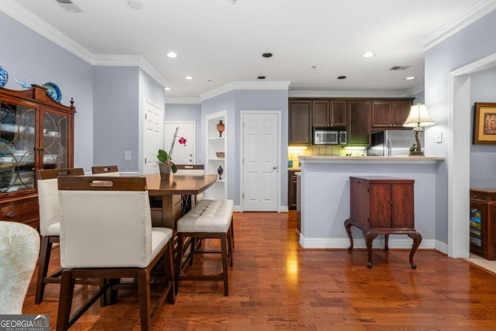 dining area with crown molding and dark hardwood / wood-style flooring