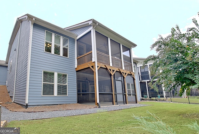 back of property with a sunroom and a lawn