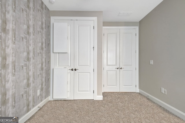 unfurnished bedroom featuring carpet floors and wooden walls