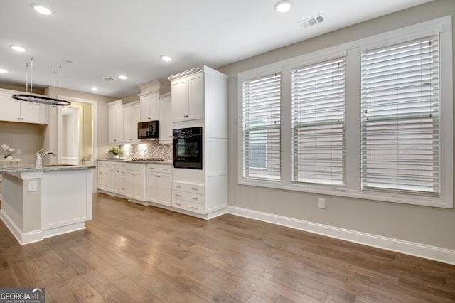 kitchen featuring decorative backsplash, white cabinetry, light stone counters, dark hardwood / wood-style flooring, and black appliances