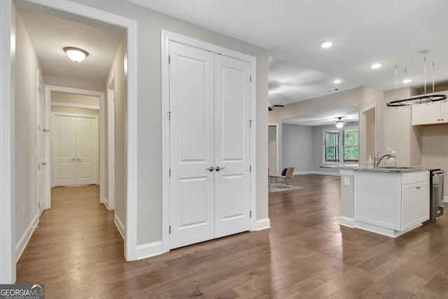 kitchen featuring ceiling fan, a kitchen island with sink, stone counters, white cabinetry, and dark hardwood / wood-style floors