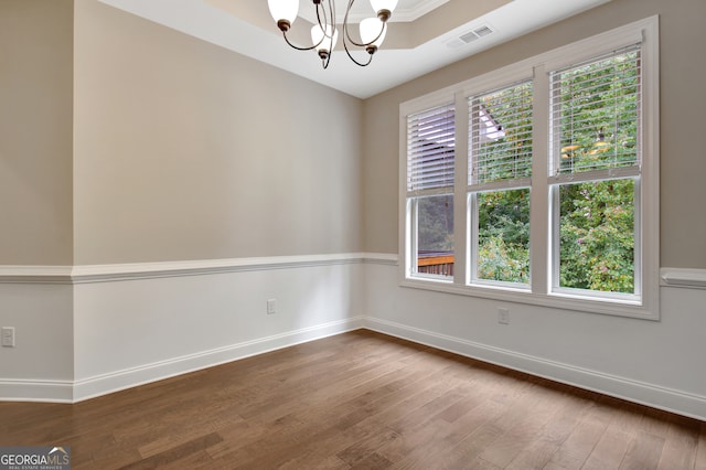 empty room with hardwood / wood-style floors and a notable chandelier