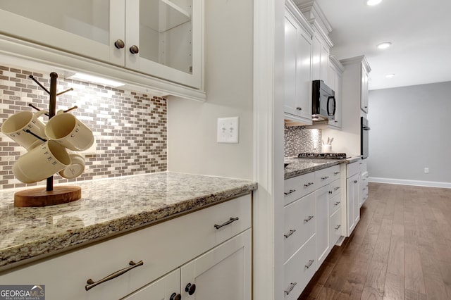 kitchen featuring light stone counters, backsplash, white cabinetry, stainless steel appliances, and dark hardwood / wood-style floors