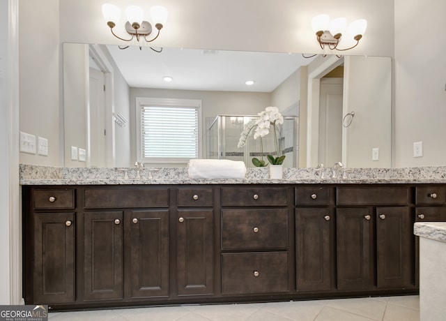 bathroom featuring an inviting chandelier, tile patterned flooring, a shower with shower door, and vanity