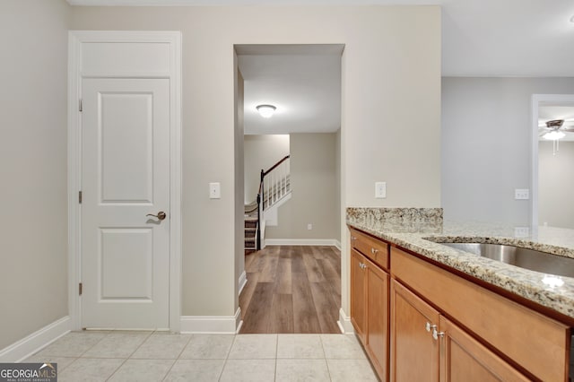 bar featuring light stone counters, light tile patterned flooring, and ceiling fan