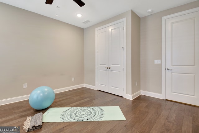 exercise area with ceiling fan and dark wood-type flooring