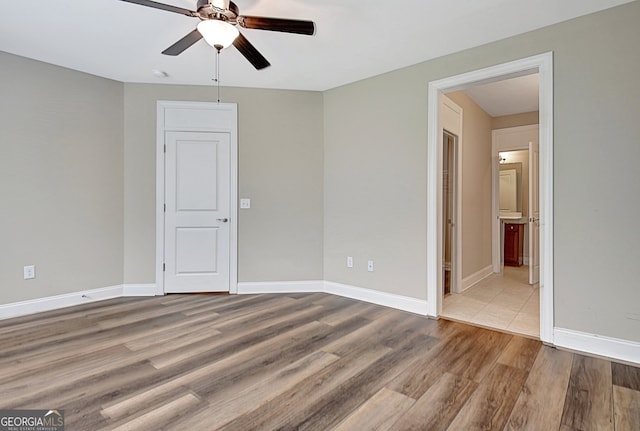 unfurnished bedroom featuring ensuite bath, light hardwood / wood-style floors, and ceiling fan