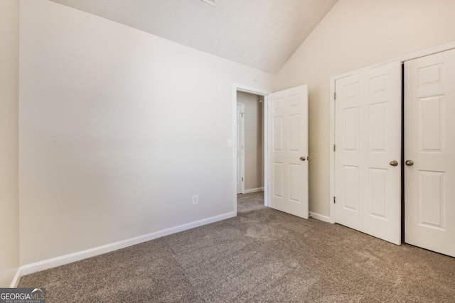 unfurnished bedroom featuring carpet floors, lofted ceiling, and a closet