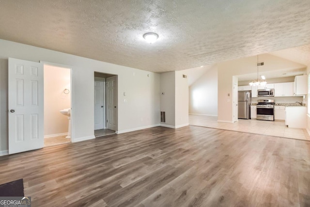 unfurnished living room featuring a textured ceiling, light wood-type flooring, and a notable chandelier