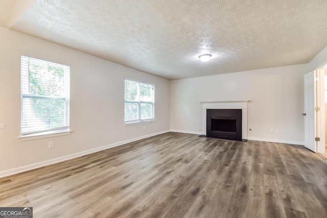 unfurnished living room featuring a textured ceiling, hardwood / wood-style floors, and a healthy amount of sunlight